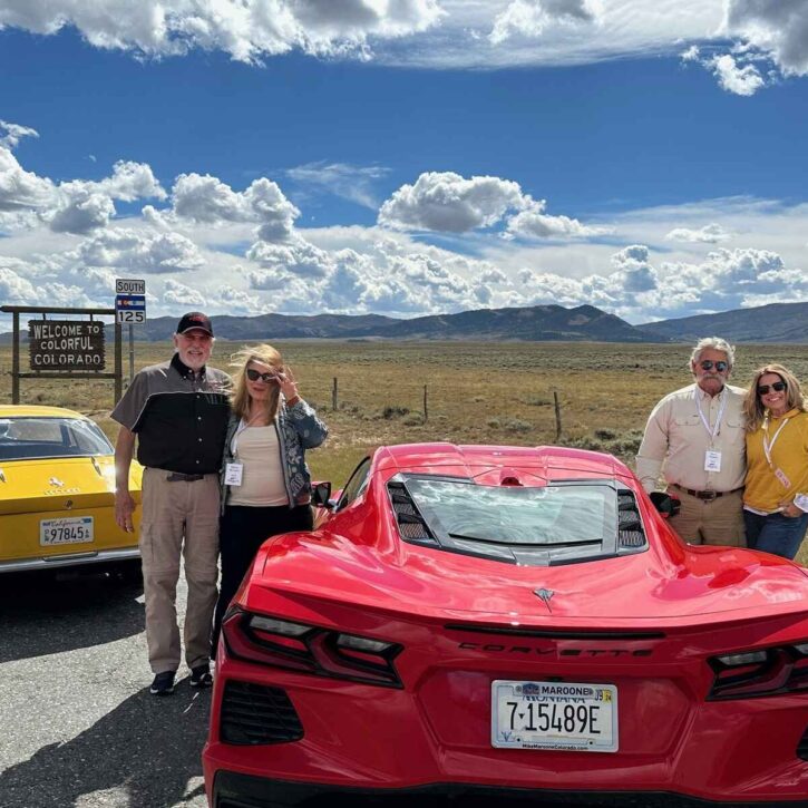 Three sports cars with participants in front of a Welcome to Colorful Colorado sign